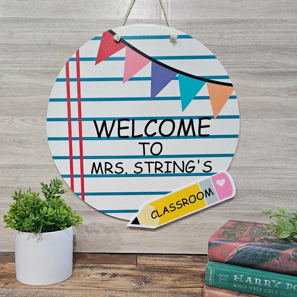 Decorative sign with 'Welcome to Mrs. String's Classroom' text on a wooden background.