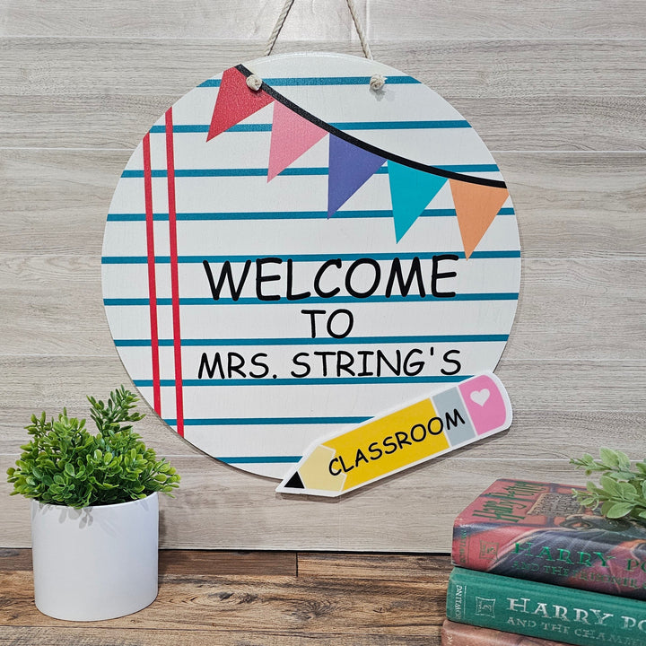 Decorative sign with 'Welcome to Mrs. String's Classroom' text on a wooden background.