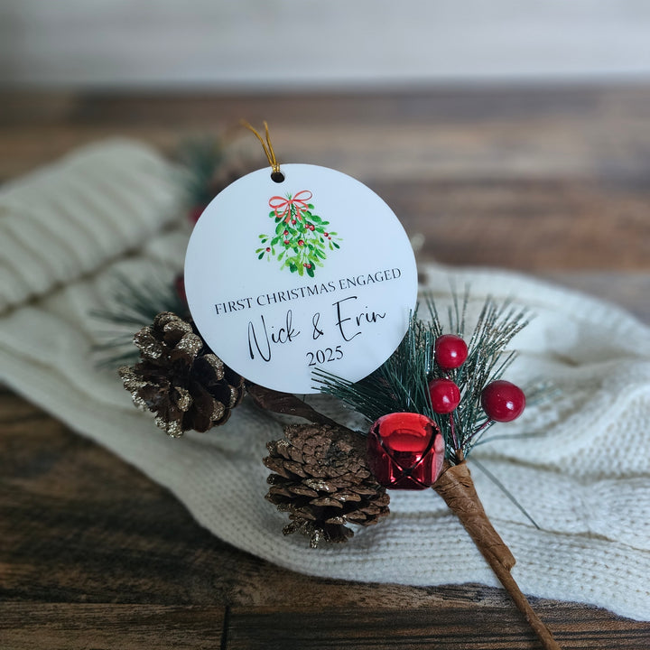 Personalized Christmas ornament with pine cones and berries on a wooden surface