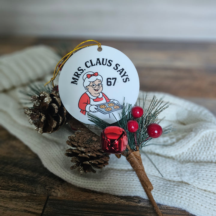 Decorative Christmas ornament with 'Mrs. Claus Says 67' text on a white background.