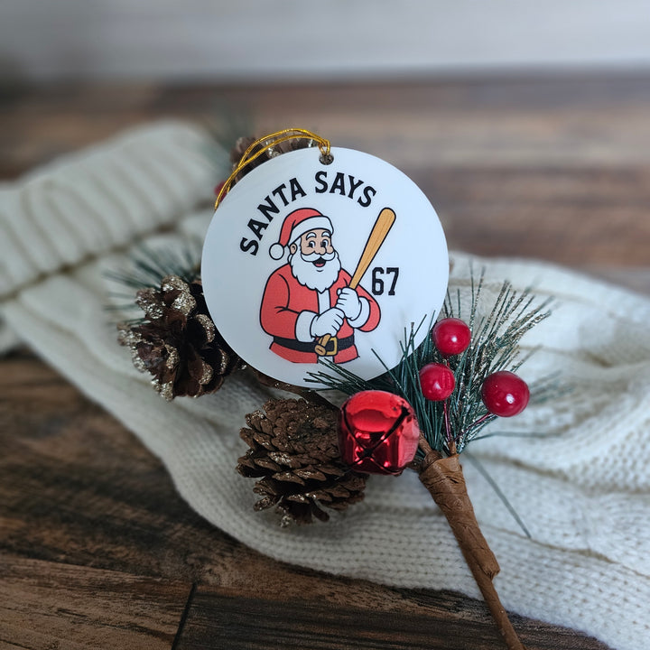 Christmas ornament with Santa Claus graphic and pine cones on a wooden surface