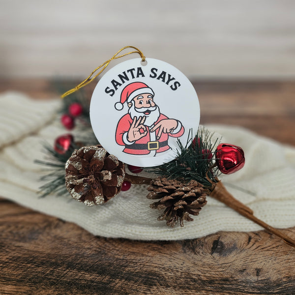 Christmas ornament with Santa Claus illustration and pine cones on a wooden surface
