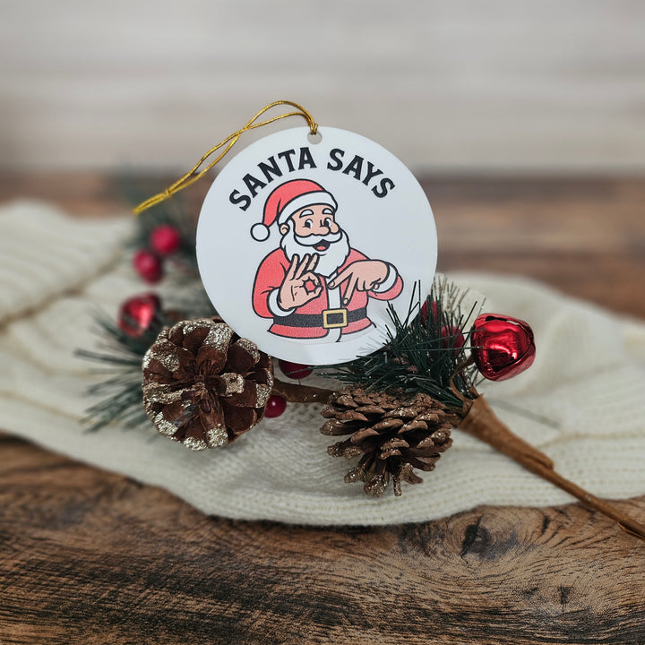 Christmas ornament with Santa Claus illustration and pine cones on a wooden surface
