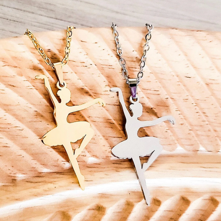 Two ballerina pendants on chains against a wooden background