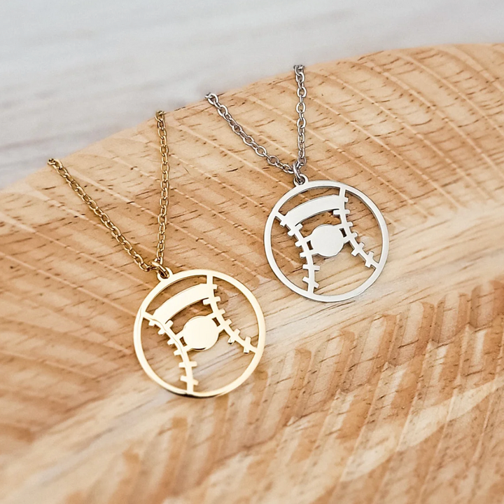 Two necklaces with baseball/softball pendants on a wooden surface