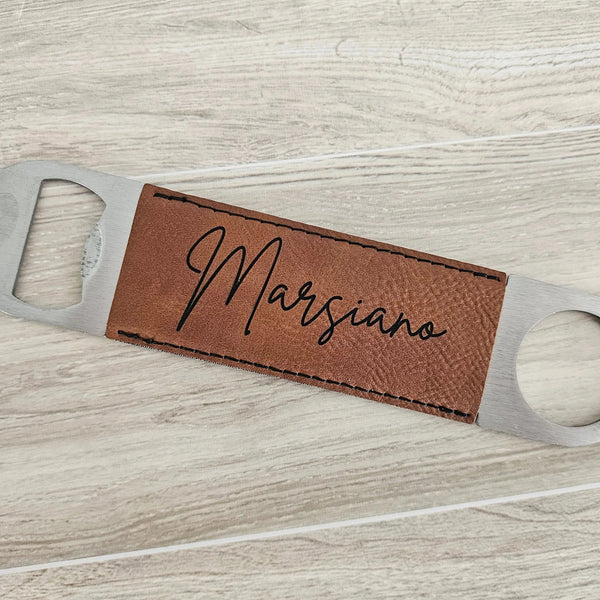 Bottle opener with brown leather tag and 'Marsiano' engraving on a light wood surface