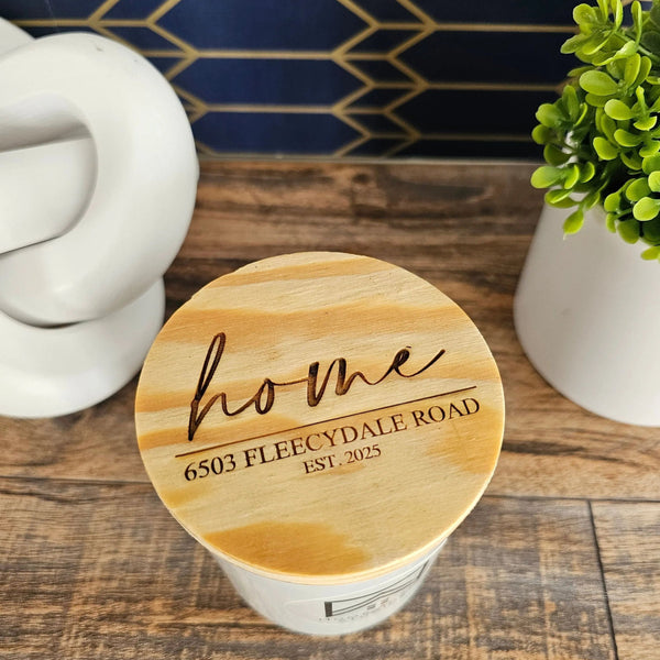 Wooden coaster with 'home' and address engraving on a wooden surface with decorative elements.