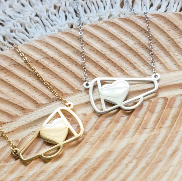 Two necklaces with geometric heart designs in megaphone on wood surface