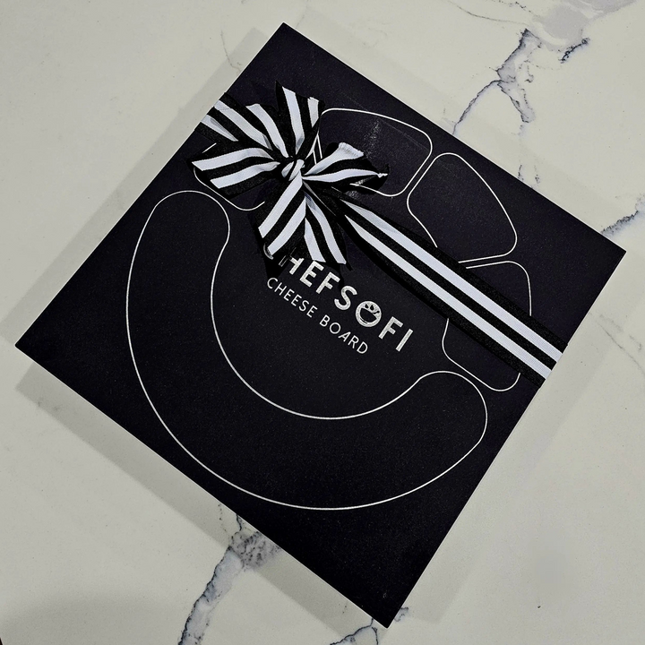 Black cheese board packaging with a bow on a marble surface