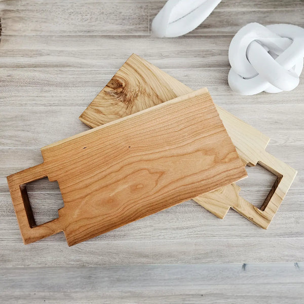 Wooden cutting board with handle on a light wooden surface