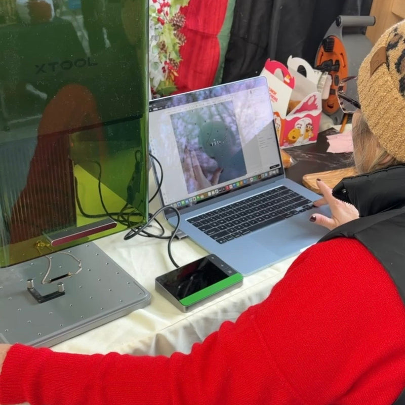 Person using a laptop on a desk with a computer monitor and various items in the background