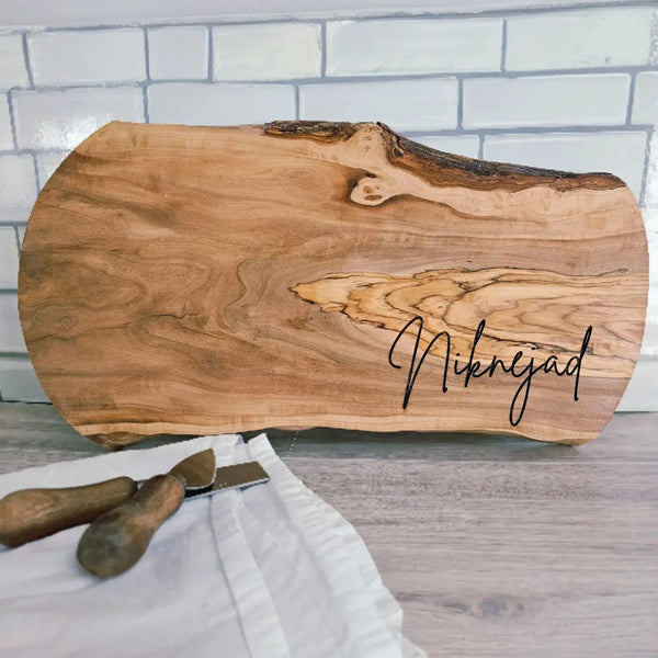 Wooden cutting board with 'Niknejad' engraving on a white brick wall background