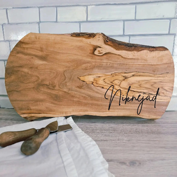Wooden cutting board with 'Niknejad' engraving on a white brick wall background